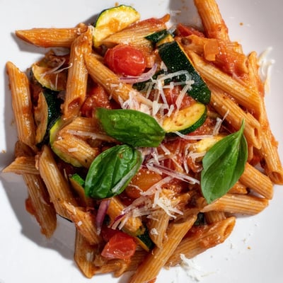 A close-up of Healthy Tomato Zucchini Pasta featuring colorful zucchini coins and cherry tomatoes in a light sauce.